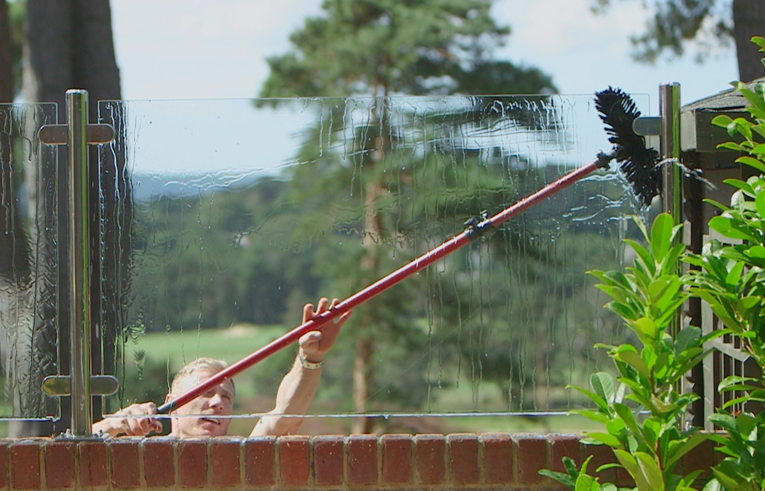 Window cleaner reaching an upstairs window with a water-fed pole
